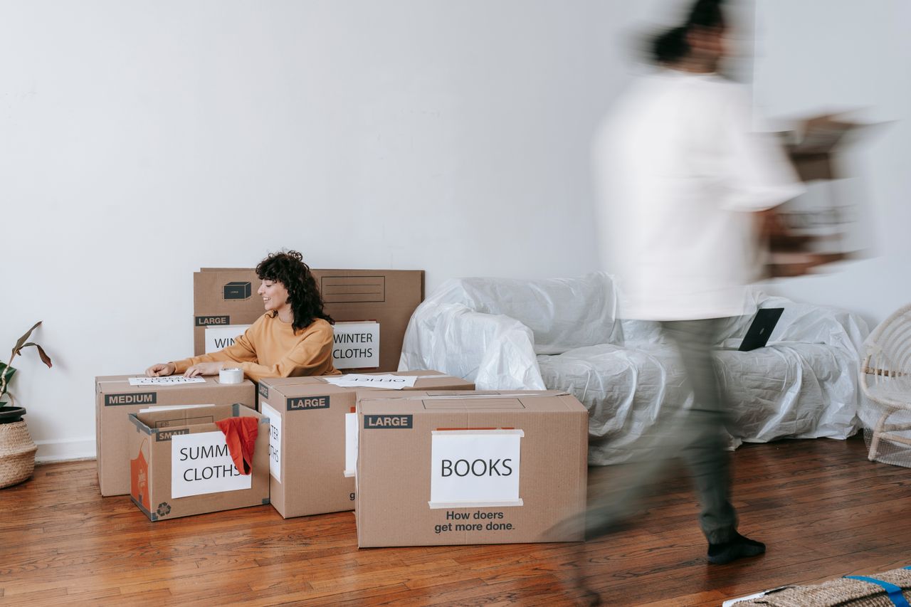 A couple is packing labeled boxes in a minimalist living room as they get ready for moving day.